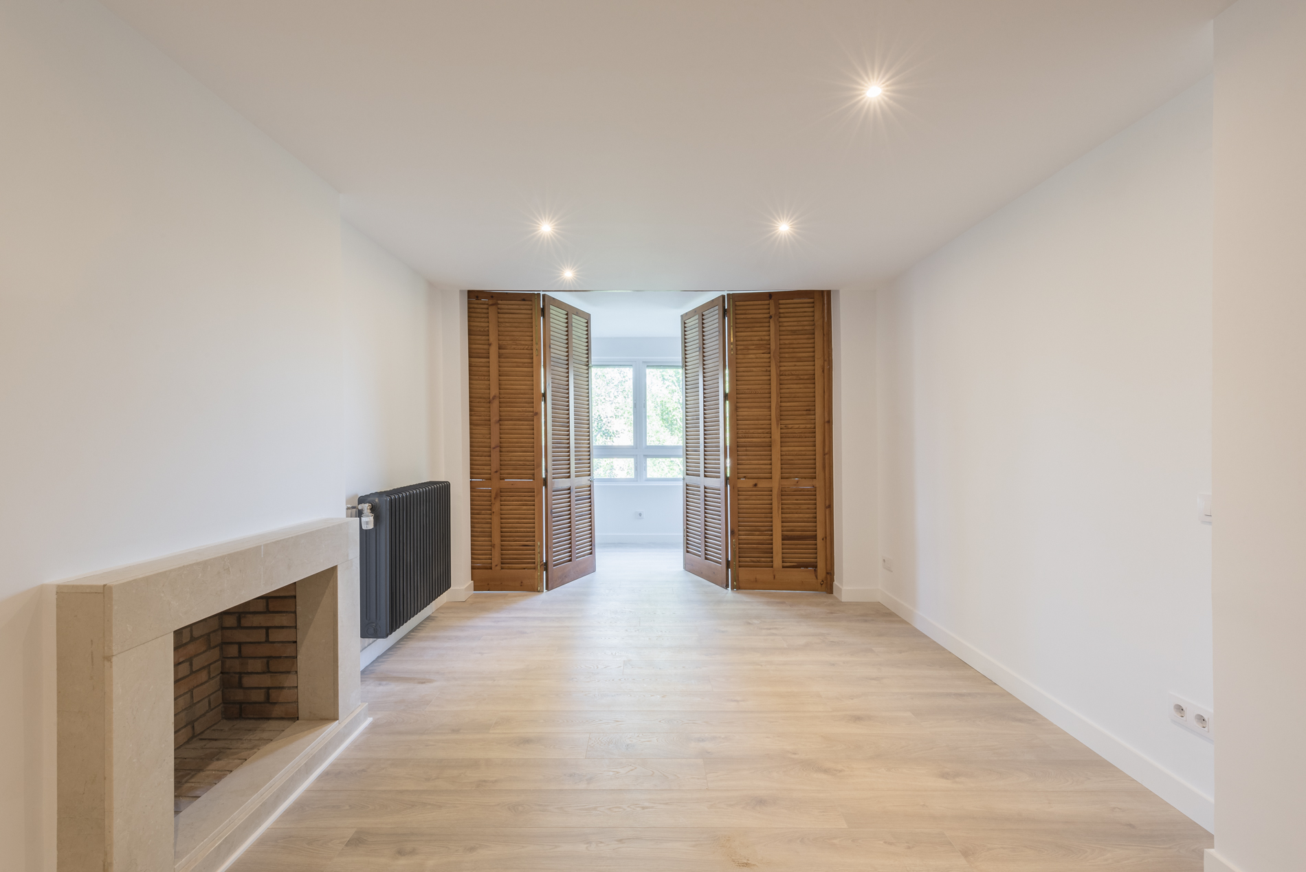 Piso de paredes blancas con chimenea y persianas marrones