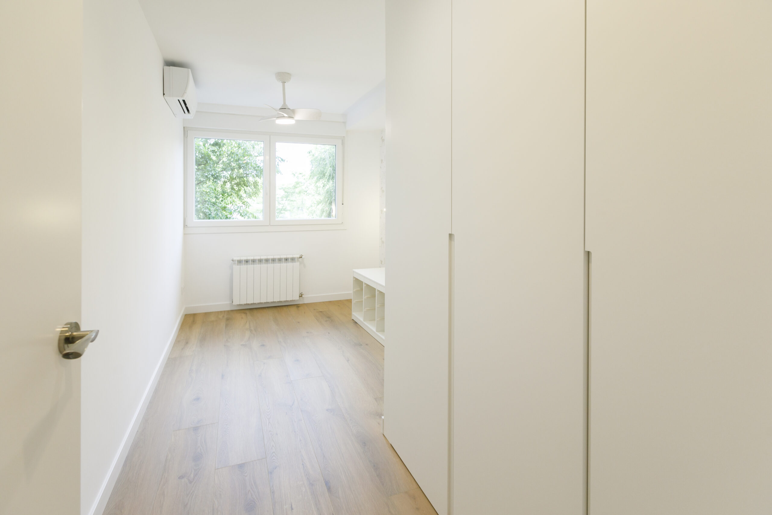 Habitación de color blanco con una ventana y un armario en el lateral