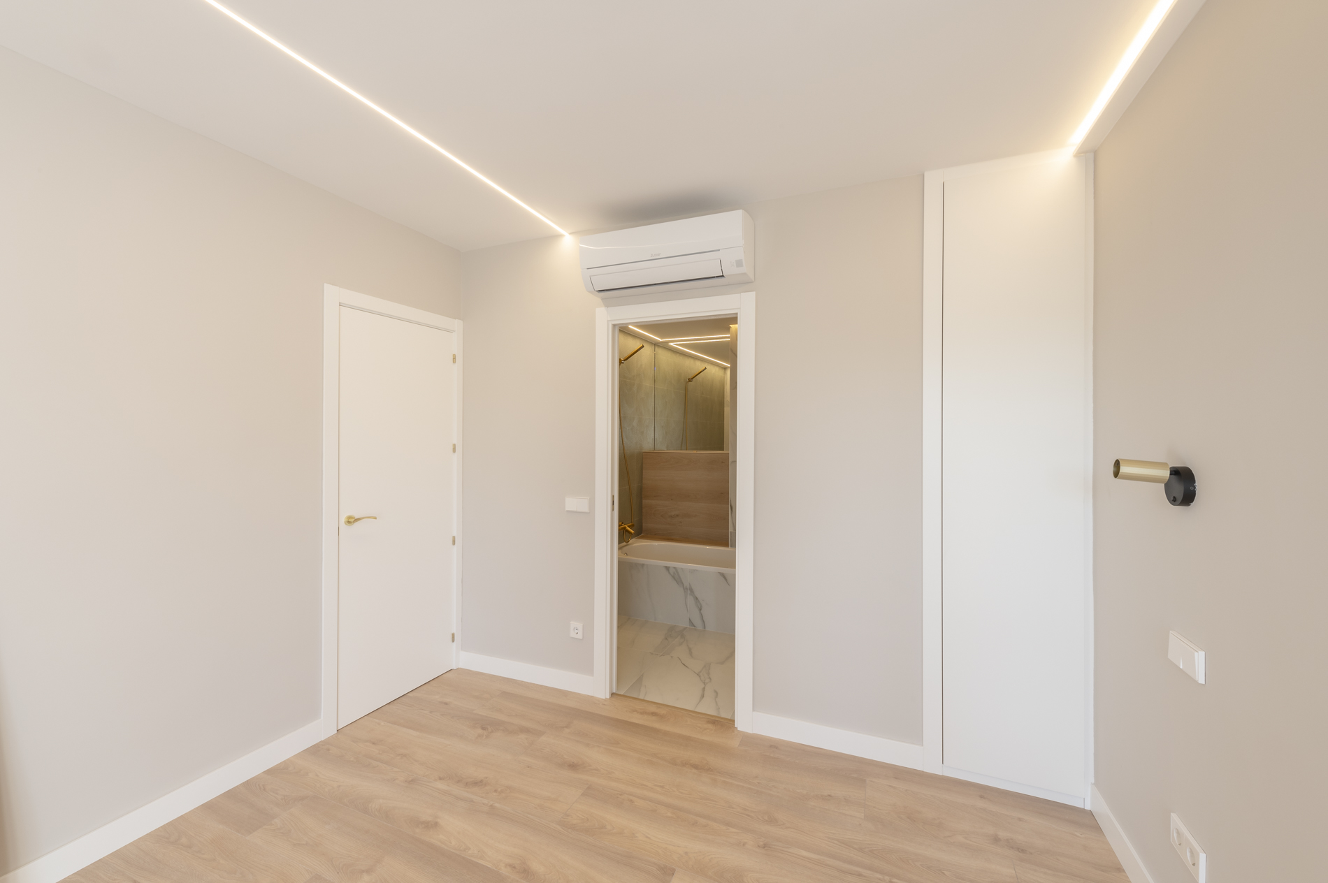 Habitación con suelo de tarima, paredes en tonos claros y luces led en el techo