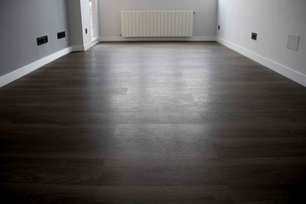 Habitación vacía con radiador y suelo de madera oscura