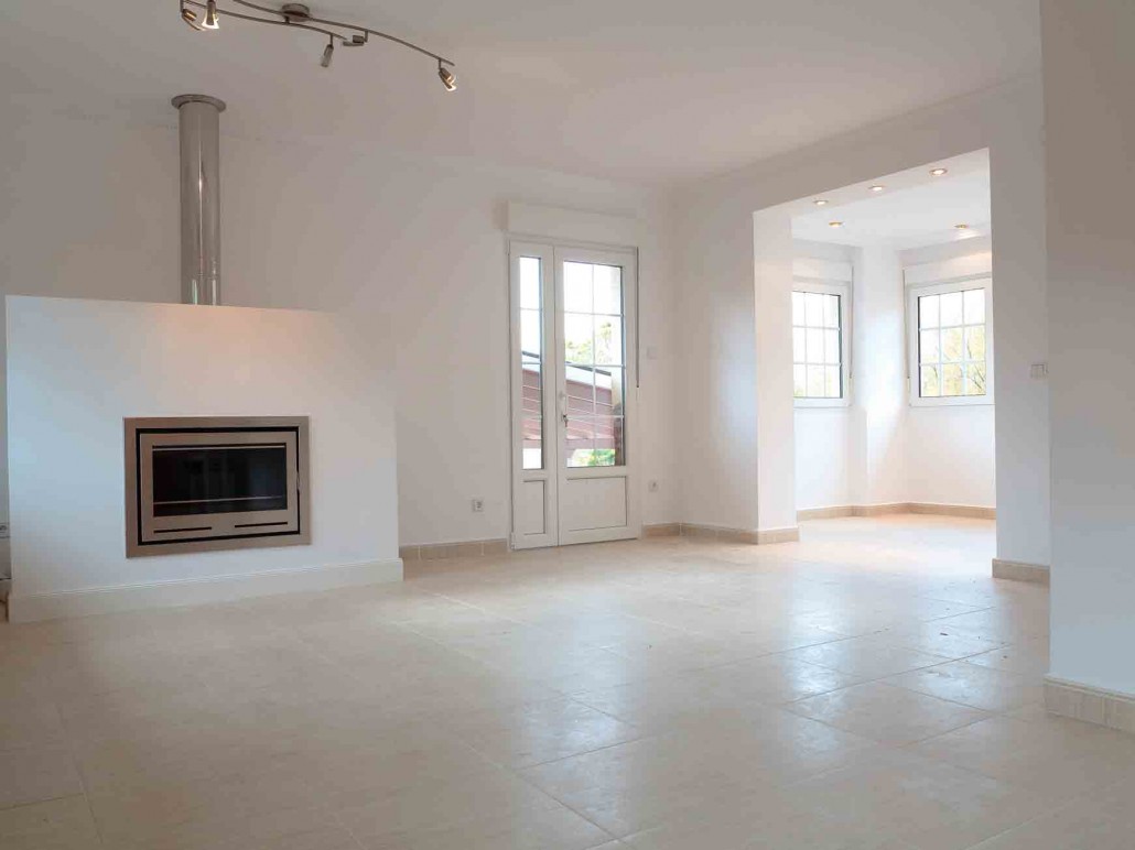 Salón blanco con ventana y chimenea