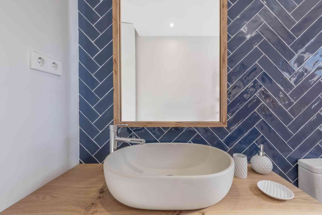 Lavabo de forma redondeada y alicatado de baño en forma de espiga en azul