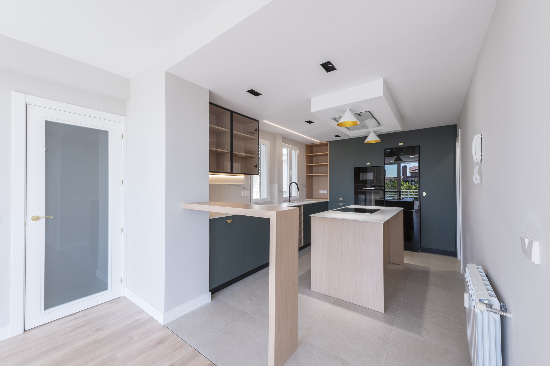 Cocina abierta al salón de color verde oscuro y madera