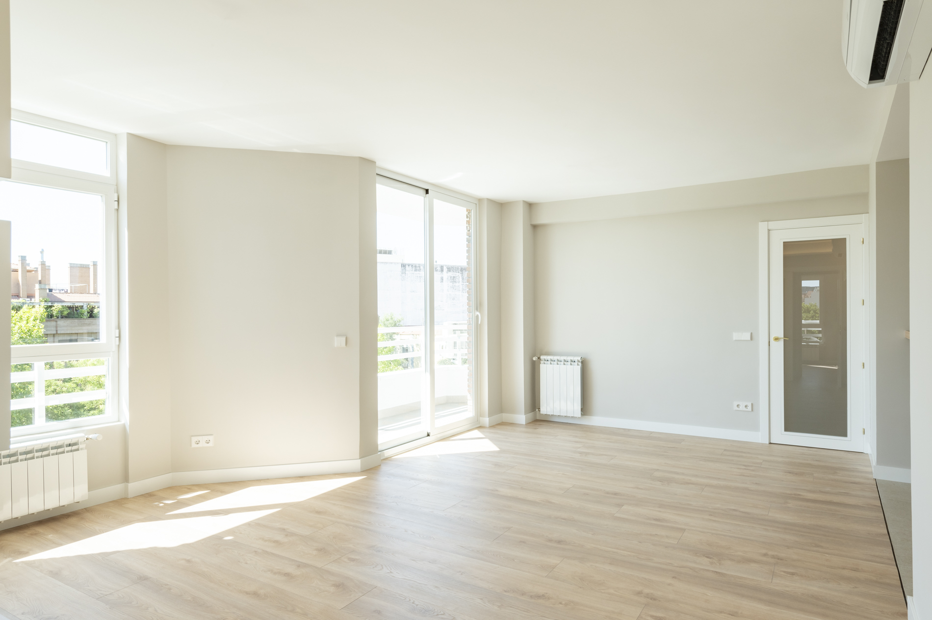 Habitación blanca con suelo de madera clara y grandes ventalanes