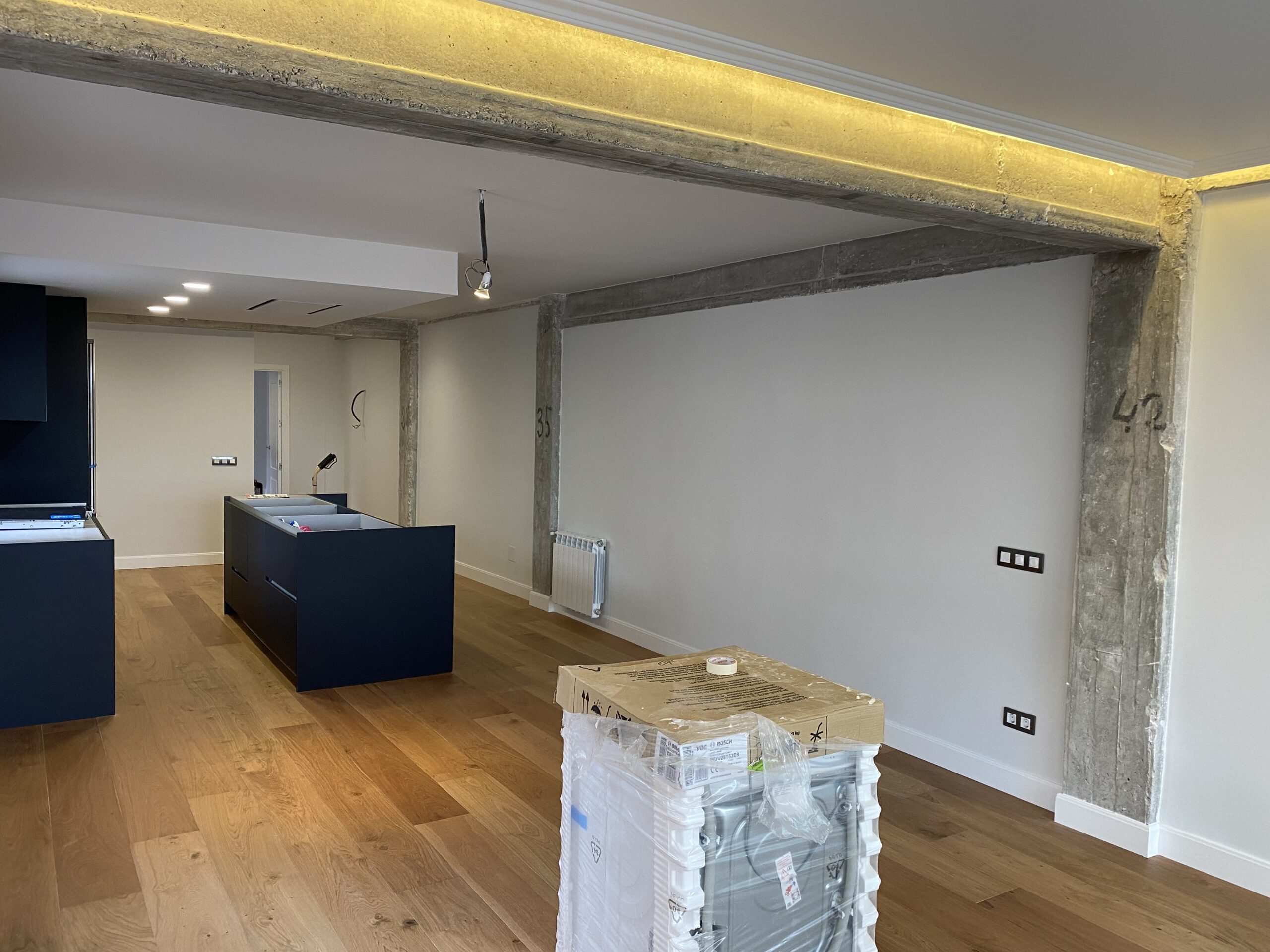 Cocina azul oscura abierta al salón con molduras en el techo